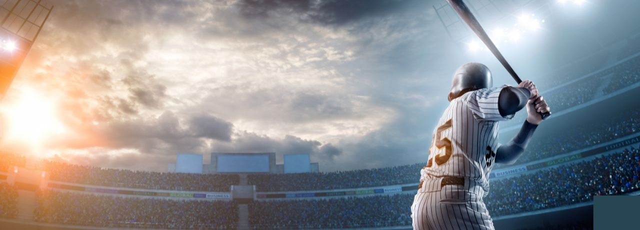 A baseball player in a striped uniform prepares to bat in a large stadium under a dramatic sky, with a crowd in the stands.
